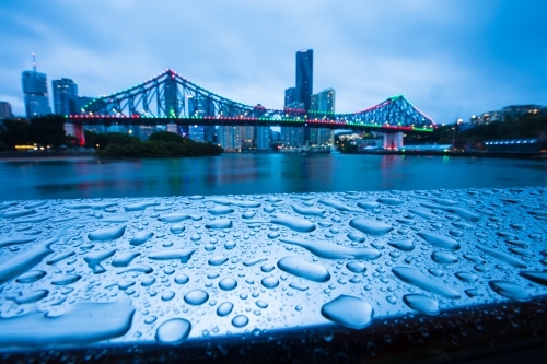 Raindrops on a metal railing with the Story Bridge in the background - Australian Stock Image