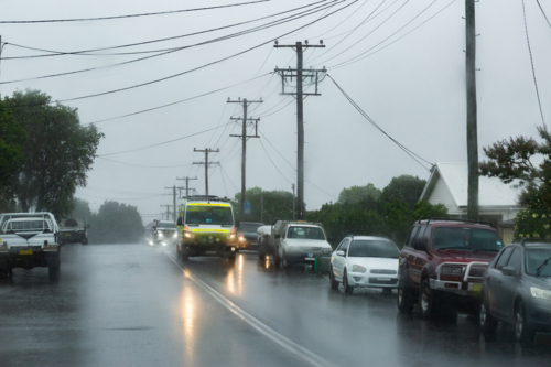 Rainy stormy day with ambulance emergency service vehicle driving on slippery wet road - Australian Stock Image