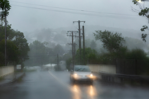 Rainy stormy day with vehicles driving on slippery wet road with low visibility conditions - Australian Stock Image