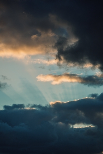 Rays of sunlight through dark clouds in the sky - Australian Stock Image