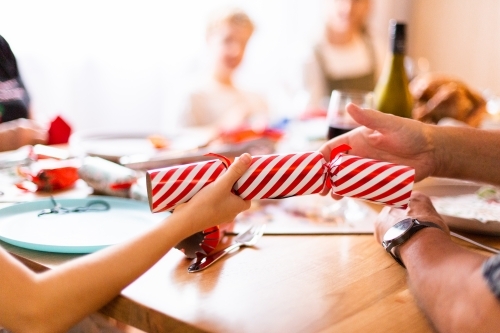 red and white Christmas cracker bon bon with child and adult hands - Australian Stock Image