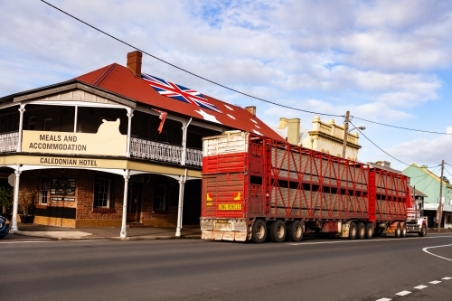 Red cattle truck livestock transport on main street of country town in Australia near pub with flag - Australian Stock Image