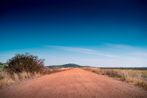 Red dirt road and big blue skies in Darwin, Northern Territory - Australian Stock Image