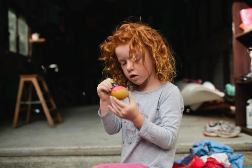 Red haired girl painting easter eggs - Australian Stock Image