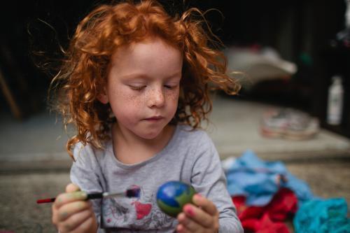 Red haired girl painting easter eggs - Australian Stock Image