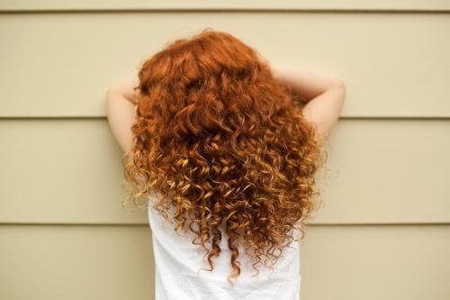 Redhead girl leaning on a wall - Australian Stock Image