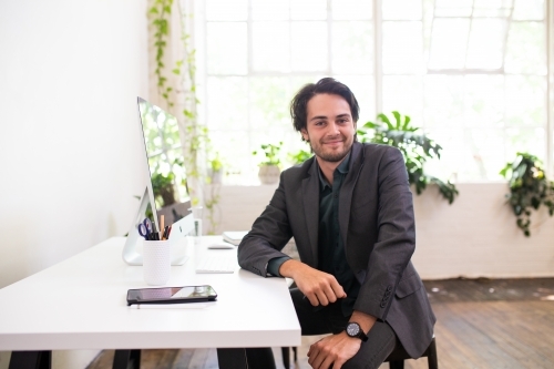 Relaxed businessman sitting and smiling in minimal creative office - Australian Stock Image