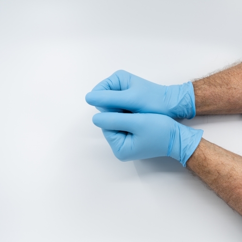 Removing blue medical gloves - Australian Stock Image