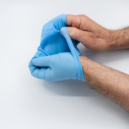 Removing blue medical gloves - Australian Stock Image