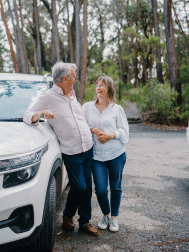 Retired senior couple standing together beside car in aussie bushland - Australian Stock Image