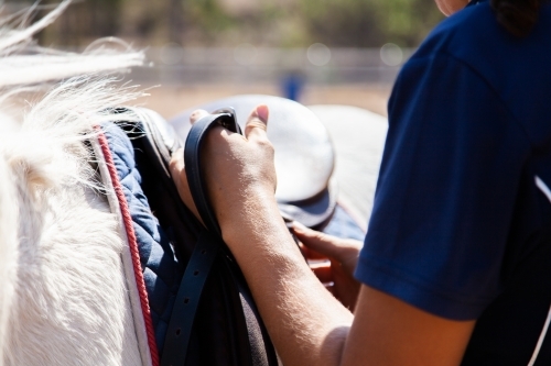 riding instructor changing stirrups on saddle - Australian Stock Image