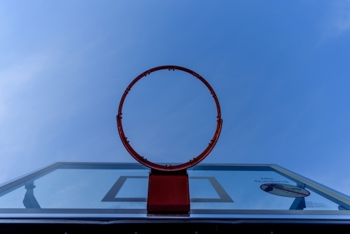 Rim of basket and backboard against blue sky, low angle shot. - Australian Stock Image