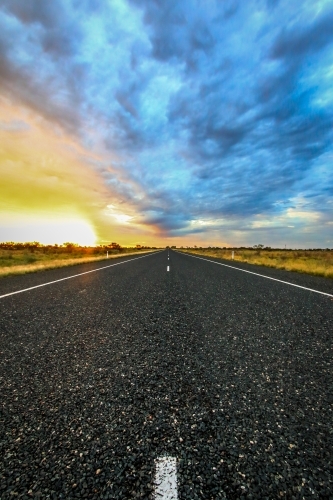 Road leading to horizon with dramatic sky - Australian Stock Image