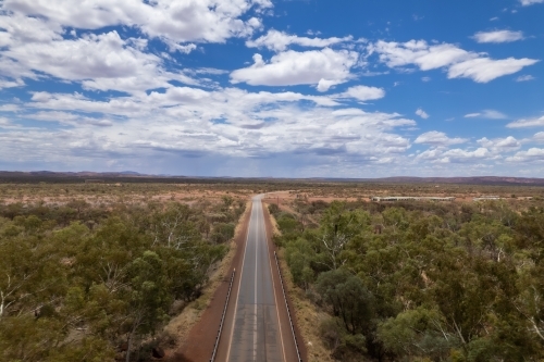 Road leading to the distance surrounded by trees - Australian Stock Image