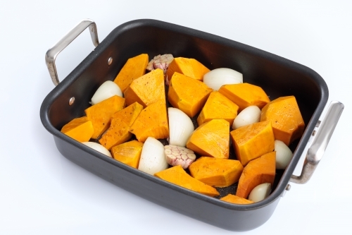 Roasting tray with pumpkin, onion and garlic - Australian Stock Image