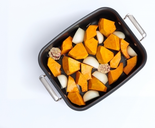 Roasting tray with pumpkin, onion and garlic - Australian Stock Image