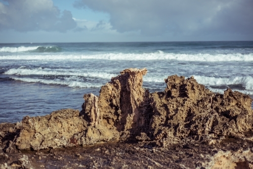 Rock formation on coast with crashing waves on overcast day