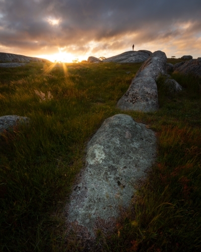 Rock formations on a field and a man standing - Australian Stock Image