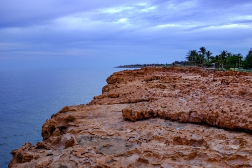 Rocky coastline and beach beneath cloudy sky - Australian Stock Image