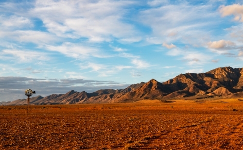 rugged ranges and windmill in late afternoon light - Australian Stock Image