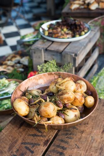 Rustic potato and olive dish on wooden table - Australian Stock Image