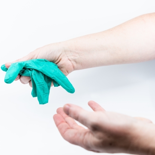 Safely removing green surgical gloves - Australian Stock Image