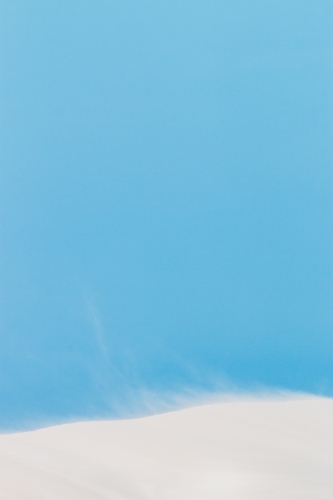 sand drifting on white dunes under blue sky vertical - Australian Stock Image