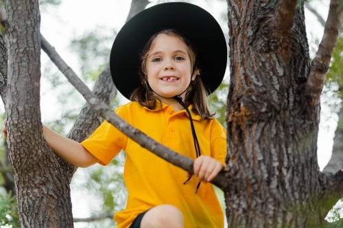 School child in Australia climbing up a tree smiling - Australian Stock Image