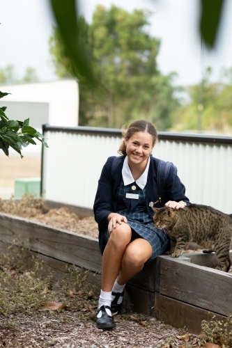 schoolgirl in uniform with her pet cat - Australian Stock Image