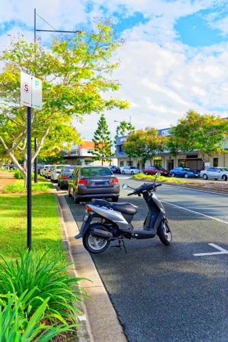 Scooter and cars parked on the side of the road in suburban area near shopping centre - Australian Stock Image