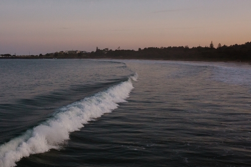 sea with waves and a silhouette shoreline in the background - Australian Stock Image