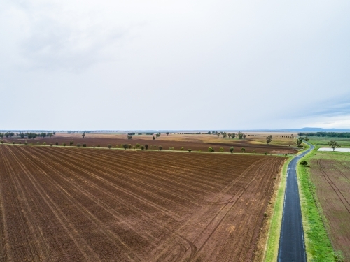 Sealed country road through brown ploughed farmland - Australian Stock Image