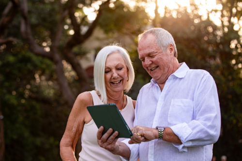 Senior couple holding and looking on a tablet outdoors - Australian Stock Image