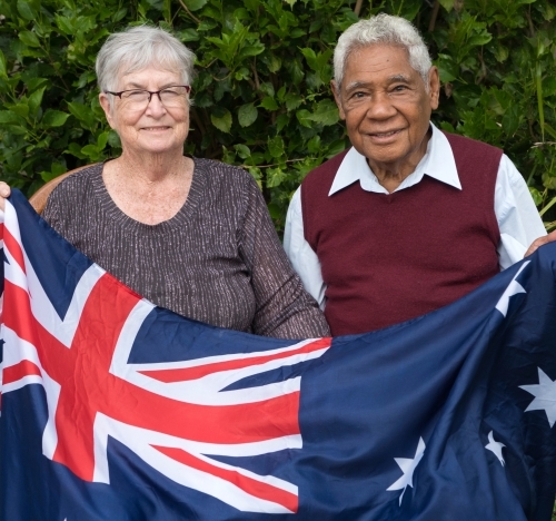 Senior married couple sitting down holding Australian flag together - Australian Stock Image