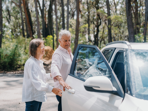 senior retiree couple opening car door in bushland parking space - Australian Stock Image