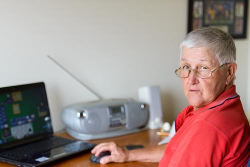 Senior woman playing on her laptop on the table - Australian Stock Image