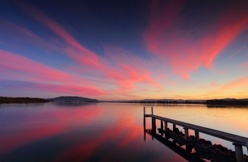 Sensational sunset across the broadwater with long jetty and reflections - Australian Stock Image