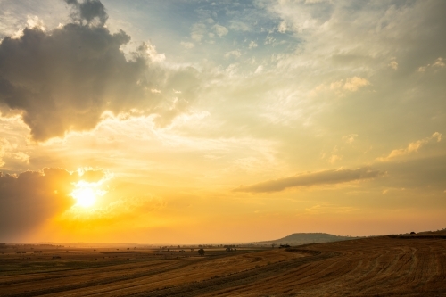 Setting yellow sun through cloud over a rural area of Queensland