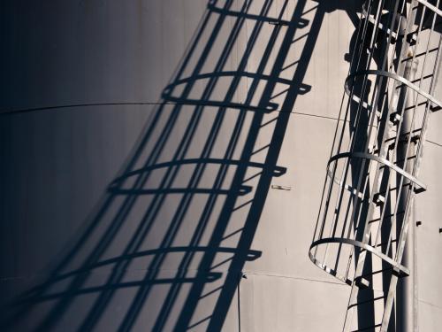 Shadow of stairway up the side of a industrial storage tank - Australian Stock Image