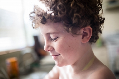 Side profile of boy's face smiling with curly hair - Australian Stock Image