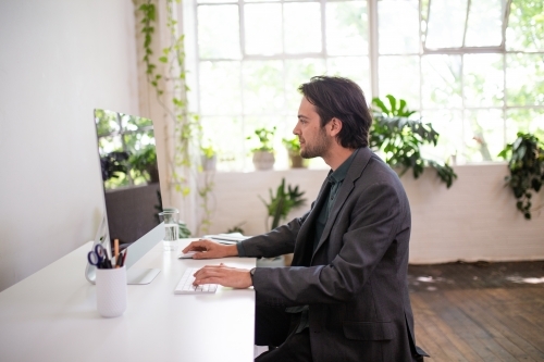 Side view of a man working on a computer in an office - Australian Stock Image