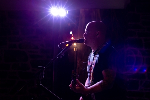 Side view of rock singer and reflection performing and lit with pink light - Australian Stock Image
