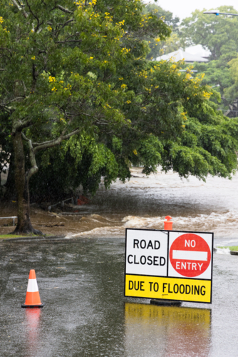 Signage across a flooded suburban road to stop traffic proceeding during a major rain event - Australian Stock Image