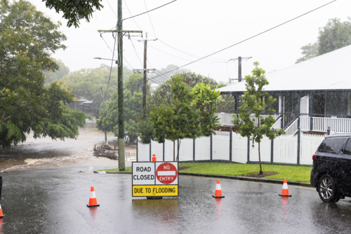 Signage across a flooded suburban road to stop traffic proceeding during a major rain flood event - Australian Stock Image