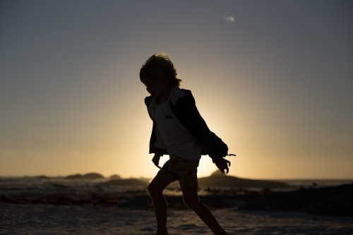 Silhouette of child running on beach - Australian Stock Image