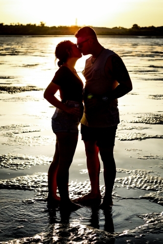 Silhouette of man and woman kissing at sunset - Australian Stock Image