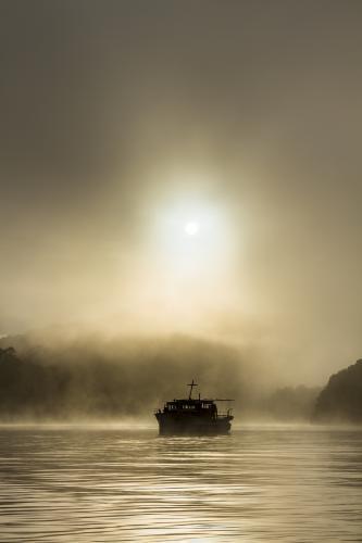 Silhouette of old wooden boat on the water in fog - Australian Stock Image