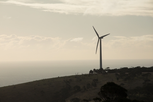 Silhouetted wind turbine on a hill in a paddock - Australian Stock Image