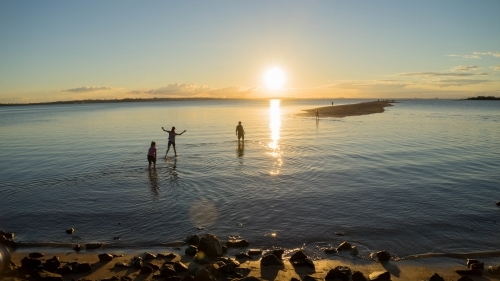 Silhouettes in water against sunset - Australian Stock Image