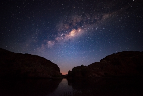 Silhouettes of two mountains under a night sky filled with stars. - Australian Stock Image